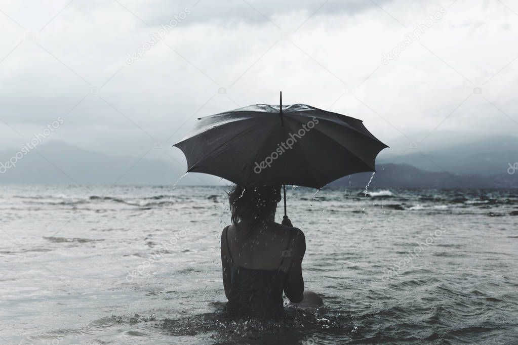 olitary woman with umbrella waiting for the storm into the sea