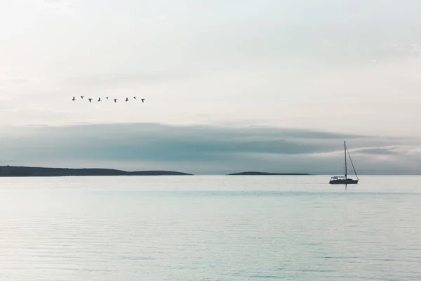 非現実的な光に照らされた海に静かに帆ボートの帆 — ストック写真