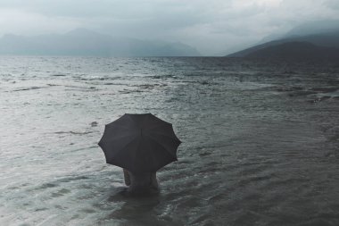 Denizde oturan yağmur bekliyor şemsiye ile yalnız kadın