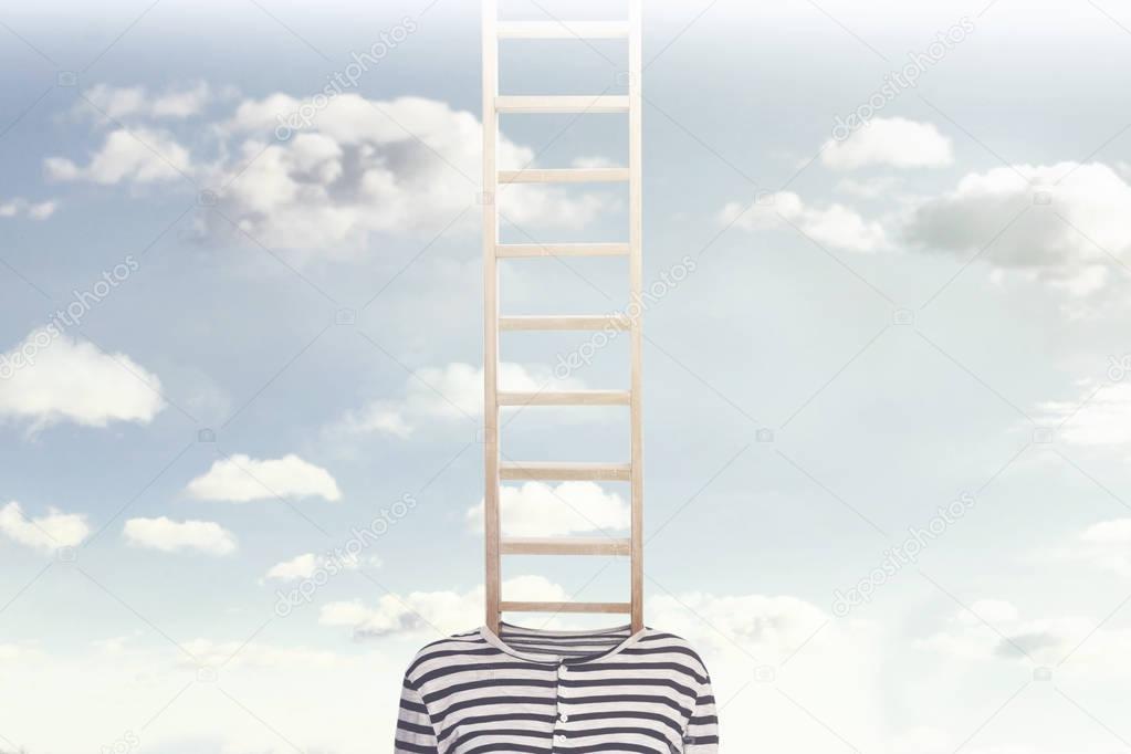 Conceptual photo with a ladder coming out of a person's body and climbing towards a cloudy sky