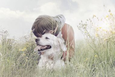küçük çocuk sevgiyle köpeğini doğa ortasında hugs