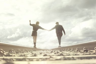 young couple walking hand in abandoned rails in a surreal place clipart