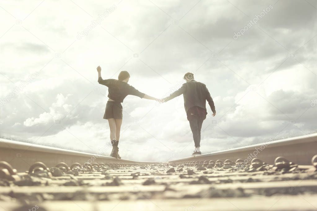 young couple walking hand in abandoned rails in a surreal place