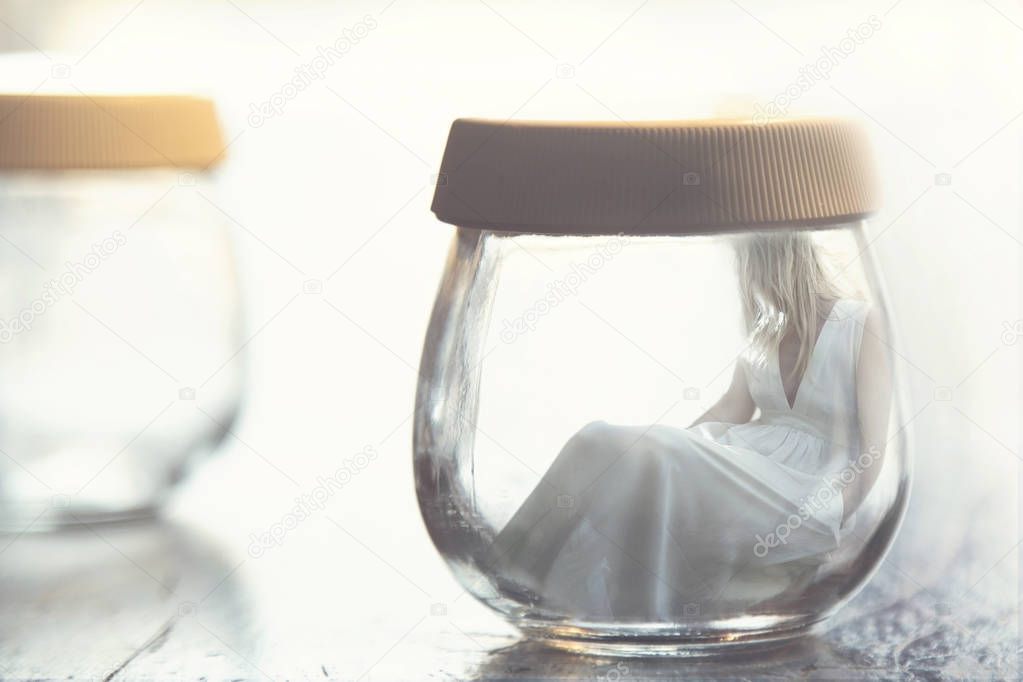 Surreal moment of a sad woman inside a glass jar