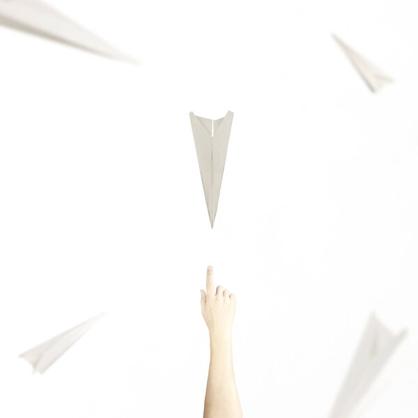 Surreal meet between a paper airplane and a hand, concept of freedom
