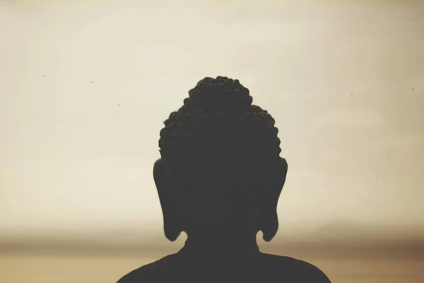 buddha in backlight in meditation towards the rising sun