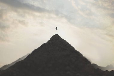  Bir adamın dağın zirvesine sıçraması, başarı kavramı.