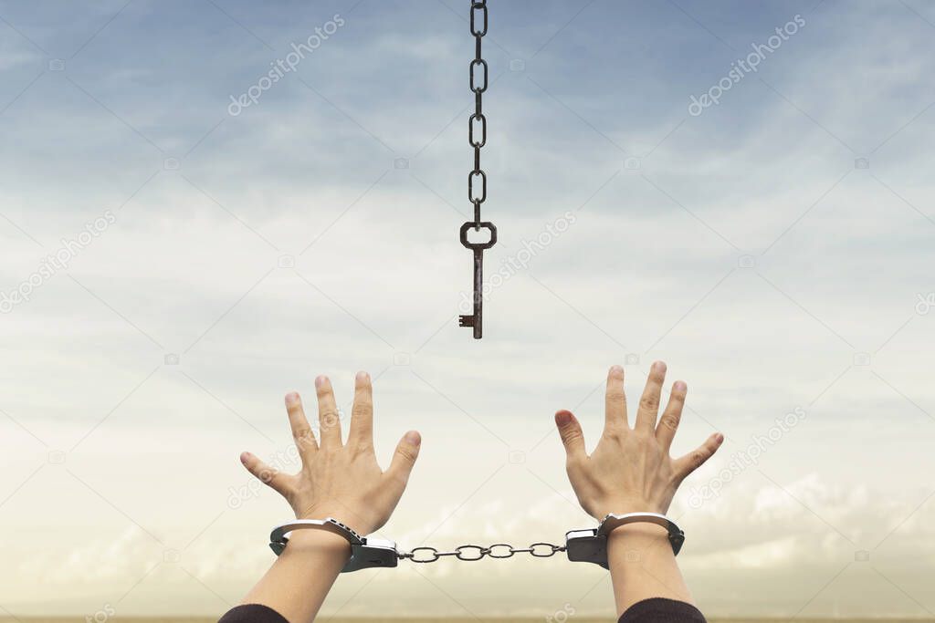 person with handcuffed hands tries to take the keys to free themselves but they are too far away