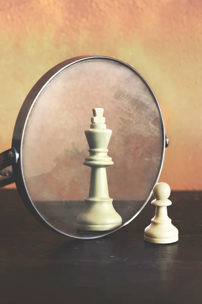 Peão do xadrez olhando no espelho e vendo o rei. conceito de