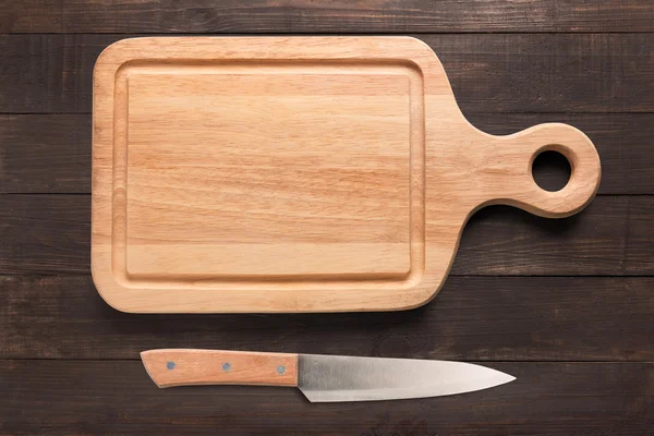 Cuchillo y tabla de cortar en el fondo de madera . — Foto de Stock