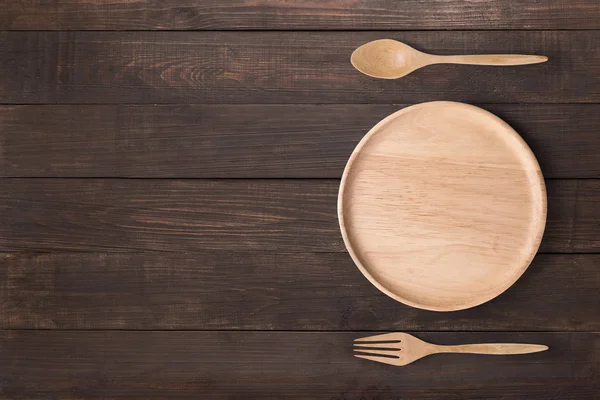 Concepto de comer. Plato de madera, cuchara de madera y tenedor de madera establecido en la w — Foto de Stock