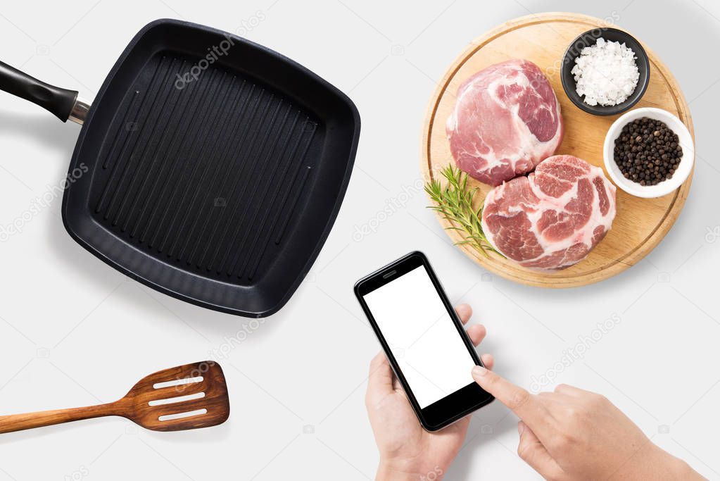 Concept of mockup using smartphone and raw pork chop steak, gril