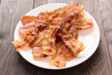 Beyaz tabakta closeup kızarmış domuz pastırması şeritler