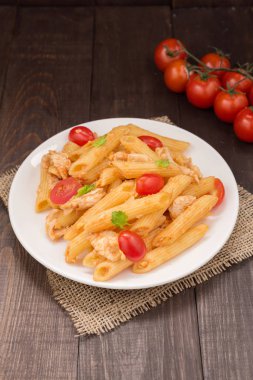 Ahşap bir masa üzerinde tavuk domates soslu Penne makarna