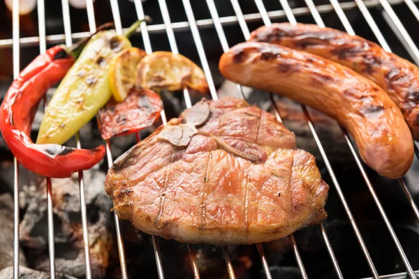 Filete de chuleta de cerdo y verduras con salchicha en un gril de barbacoa en llamas —  Fotos de Stock