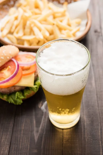 Cerveza que se vierte en un vaso con hamburguesas gourmet y papas fritas . — Foto de Stock