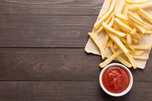 Batatas fritas com ketchup em fundo de madeira — Fotografia de Stock