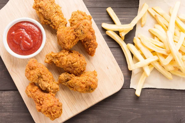 Fried chicken drumstick and french fries on wooden background — Stock Photo, Image