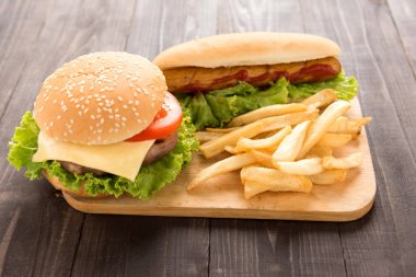 Sosisli sandviç, hamburger ve patates kızartması ahşap arka plan üzerinde