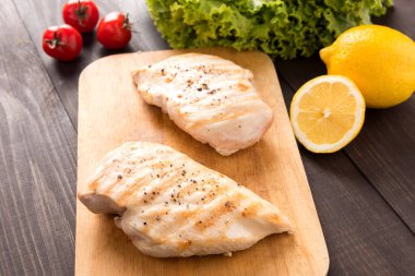 Ahşap masa üzerinde marine edilmiş ızgara tavuk göğsü