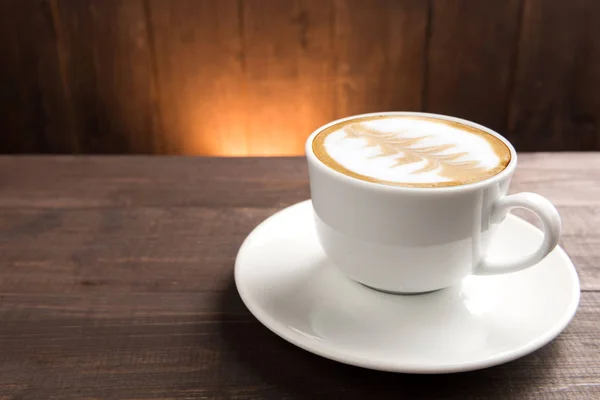 Een kopje koffie op houten ondergrond — Stockfoto