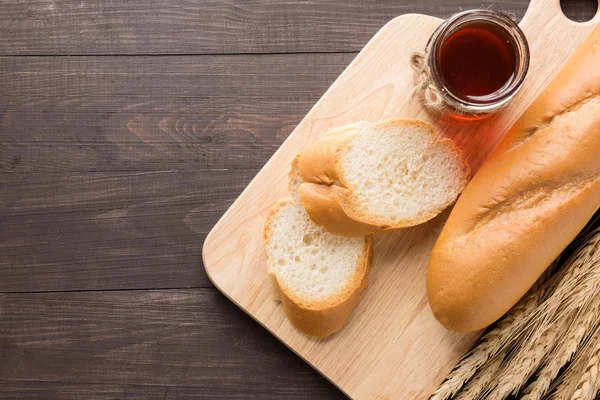 Rusztikus kenyér vagy baguette, mézzel, a fából készült háttér — Stock Fotó