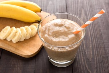 Muz smoothie ve ahşap zemin üzerine taze muz.