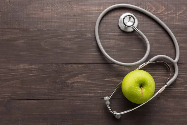 Concept voor gezondheidszorg, stethoscoop en groene appel op houten ba — Stockfoto
