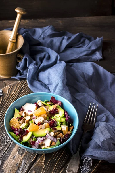 Ensalada de naranja, aguacate, queso azul, pollo y cebolla en un bol azul sobre fondo de madera . — Foto de Stock