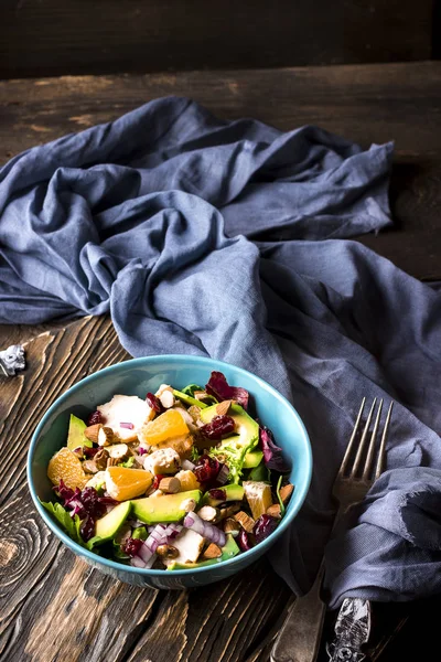 Ensalada de naranja, aguacate, queso azul, pollo y cebolla en un bol azul sobre fondo de madera . — Foto de Stock