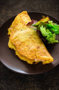 Seramik plaka üzerinde omlet ve yeşil salata.