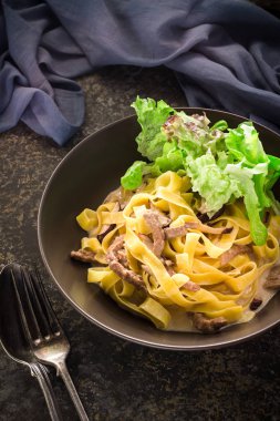 Seramik kase içinde et ve yeşil salata ile makarna. 