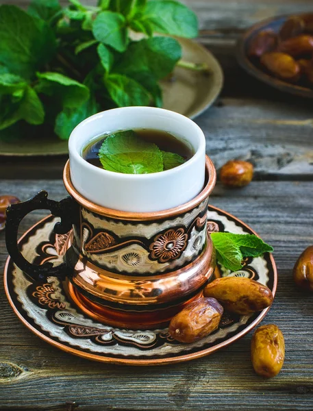 Τσάι με μέντα σε Αραβικά στυλ και τις ημερομηνίες στο ξύλινο τραπέζι. — Φωτογραφία Αρχείου