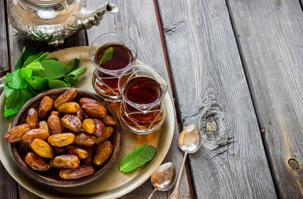 Chá com hortelã em estilo árabe e tâmaras em mesa de madeira . — Fotografia de Stock