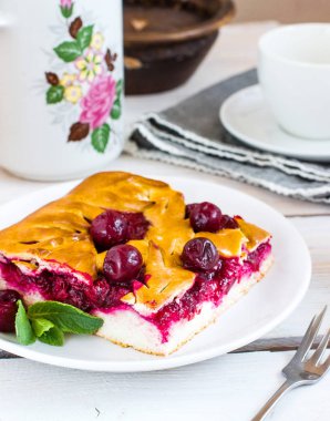 Beyaz plaka tarihinde kirazlı turta. Ahşap arka plan.