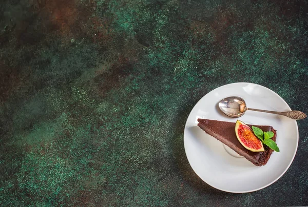Chocolate cheesecake with fig on green slate background. — Stock Photo, Image