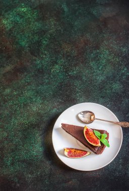 Yeşil arduvaz arka plan üzerinde incir ile Çikolatalı cheesecake. 