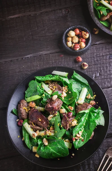 Ensalada verde con hígado y espinacas sobre fondo rústico oscuro . — Foto de Stock