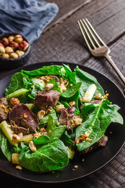 Ensalada verde con hígado y espinacas sobre fondo rústico oscuro . — Foto de Stock