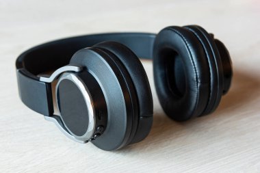 Tahta bir yüzeyde siyah kablosuz kulaklıklar.. 