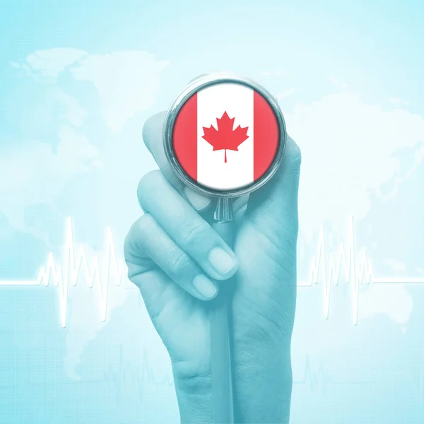 Ręka lekarza przytrzymanie stetoskop z flagą Kanada. — Zdjęcie stockowe
