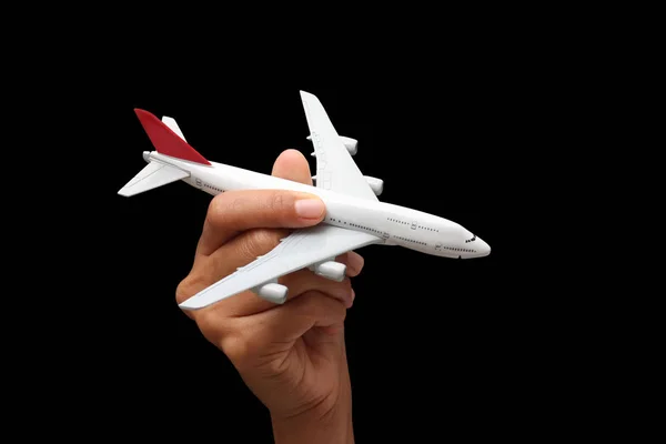 Hand met een model vliegtuig op een zwarte achtergrond. — Stockfoto