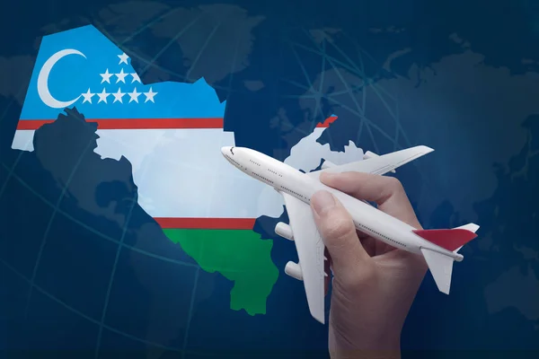 Mână care ține avionul cu harta Uzbekistanului . — Fotografie, imagine de stoc
