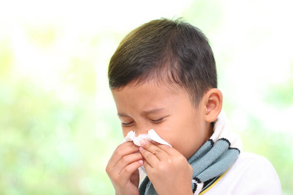Little boy blowing his nose into tissue. healthcare and medical concept.