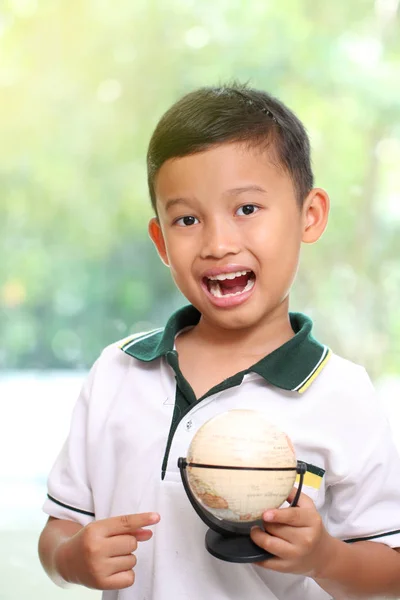 Маленький мальчик держит глобус на зеленом фоне — стоковое фото