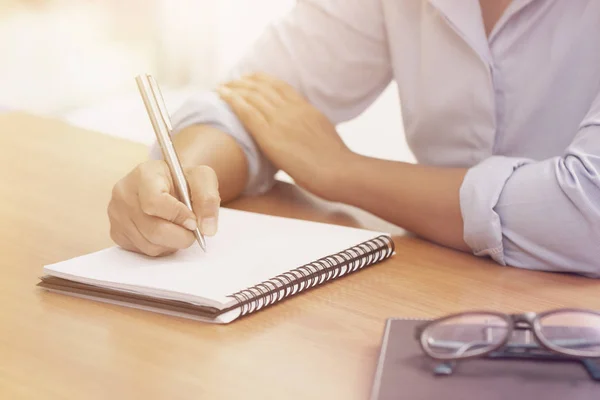 Business kvinna hand skriva på anteckningsboken på kontoret — Stockfoto
