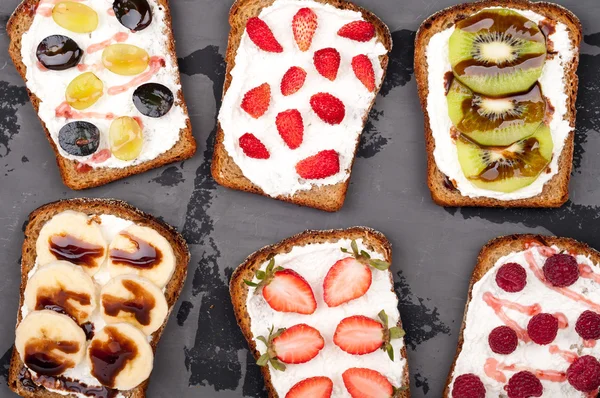 Une saine alimentation. Sandwichs sucrés avec fromage à la crème et baies fraîches et fruits sur fond blanc. Petit déjeuner grillé. Vue du dessus — Photo