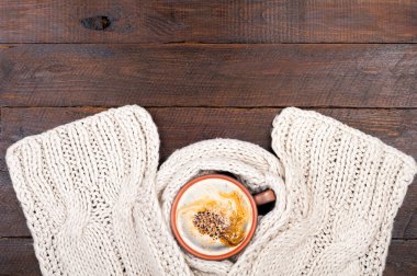 Sıcak kahve fincanı ve el yapımı örgü yün, İpek eşarp ahşap arka plan üzerinde. Kış giysileri. Kavramı rahat bir atmosfer ile bir fincan kahve kışın. Kopya alanı