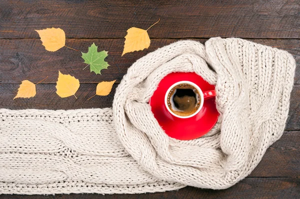 Hot coffee cup and handmade knitted woolen scarf on wooden background. Autumn or winter clothes. Concept cozy autumn atmosphere with a cup of coffee — Stock Photo, Image