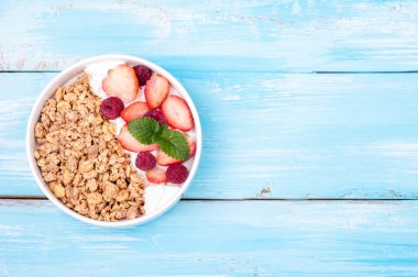 Granola kahvaltıda yoğurt ve meyveler - çilek ve ahududu ahşap arka plan üzerinde. Yulaf ezmesi yeme sağlıklı. Üstten Görünüm